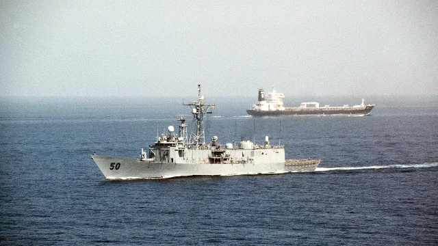 A port view of the guided missile frigate USS TAYLOR (FFG-50) as it passes a tanker after going through the Strait of Hormuz…