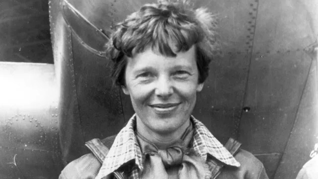 Amelia Earhart standing under nose of her Lockheed Model 10-E Electra.