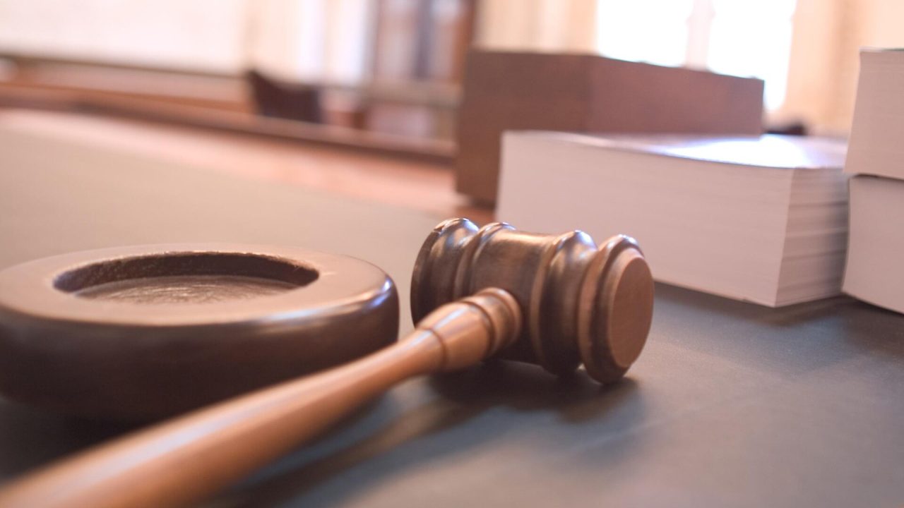 A wooden gavel rests on a courtroom table.