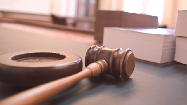 A wooden gavel rests on a courtroom table.