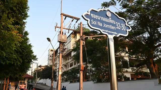 Street sign reading Soi Na Jomtien 32-30 marks a quiet urban lane lined with trees power lines and apartment buildings at go…