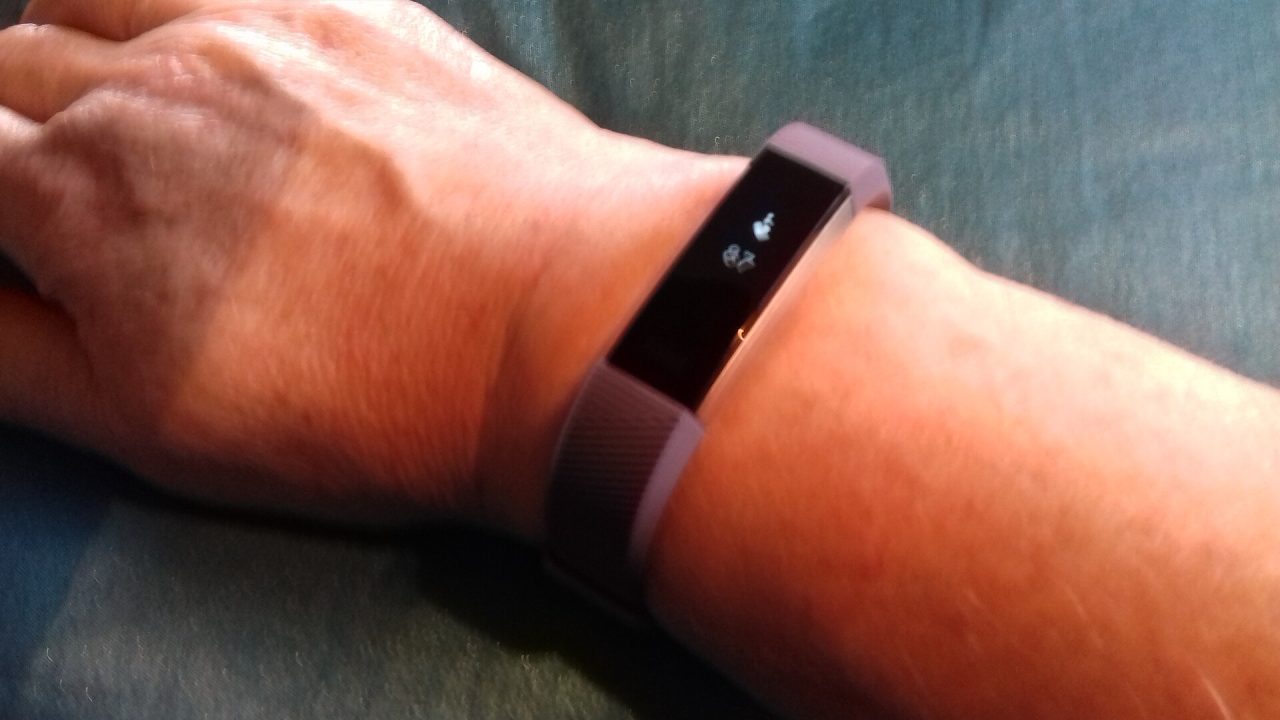 Fitbit Alta HR fitness tracker wristband showing heart rate monitor display.