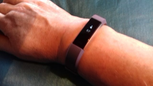 Fitbit Alta HR fitness tracker wristband showing heart rate monitor display.