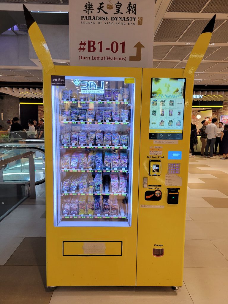 Vending machine in Singapore selling packs of Pokemon and One Piece trading cards.